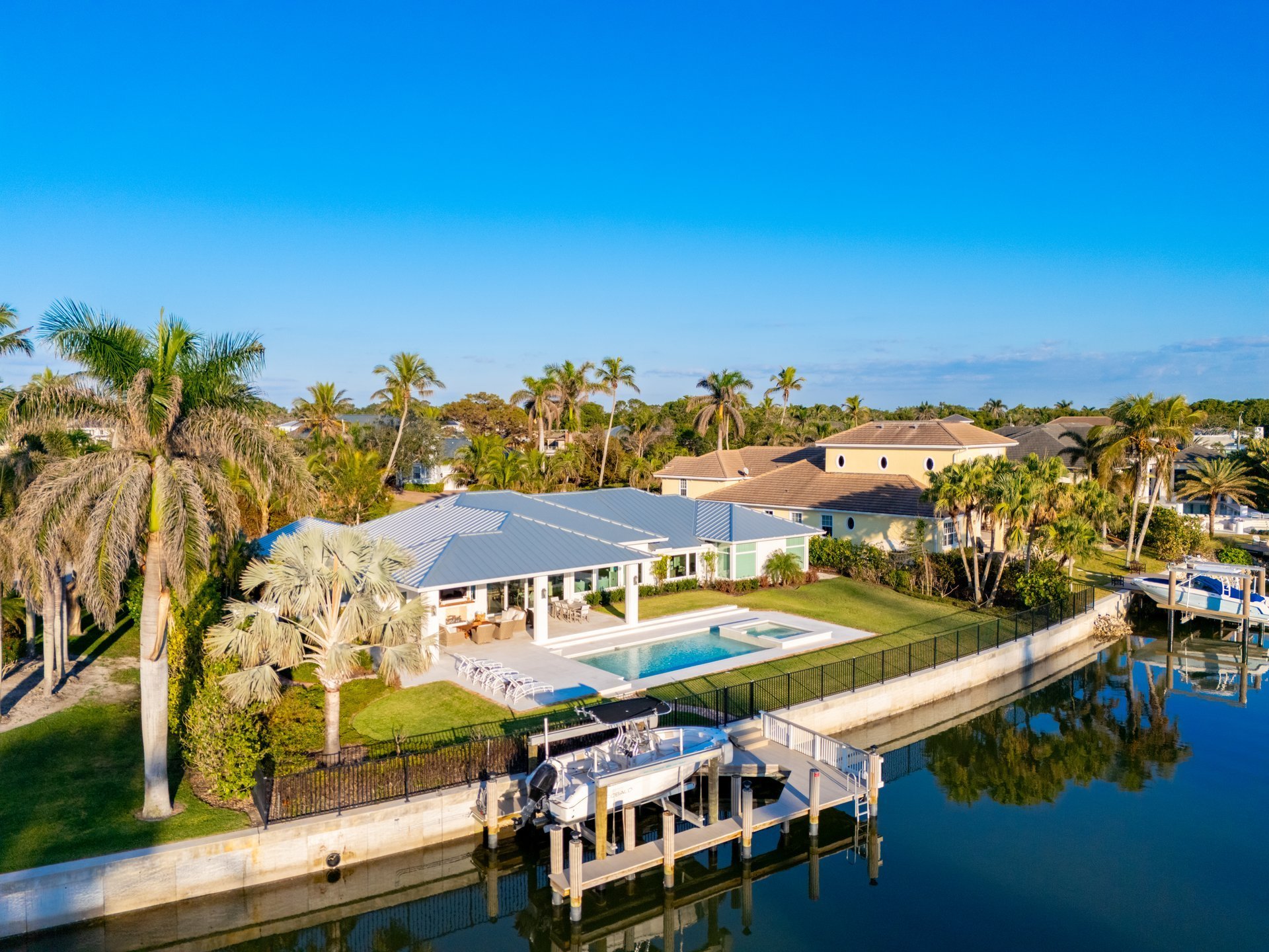 Naples, FL luxury waterfront mansion home with beautiful tropical landscaping and dock
