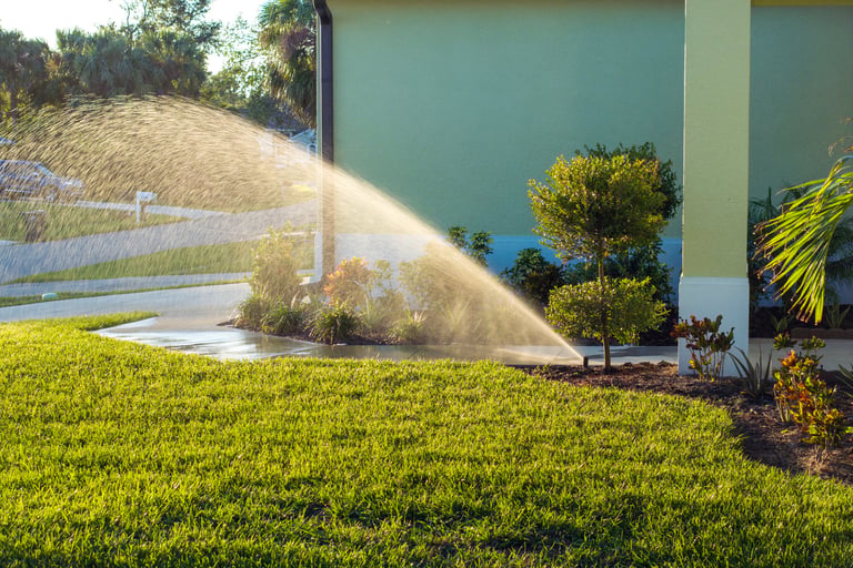 Lawn grass being watered with automated sprinkler during dry season