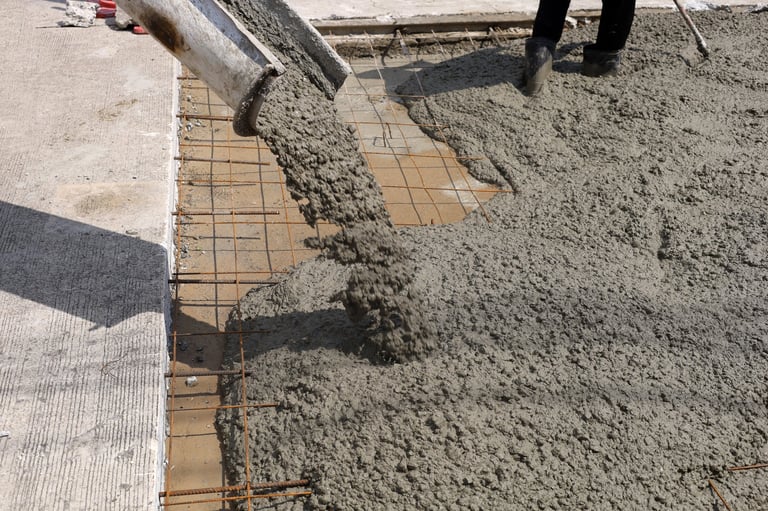 Wet cement pouring from mixer truck chute onto steel wire mesh for new driveway